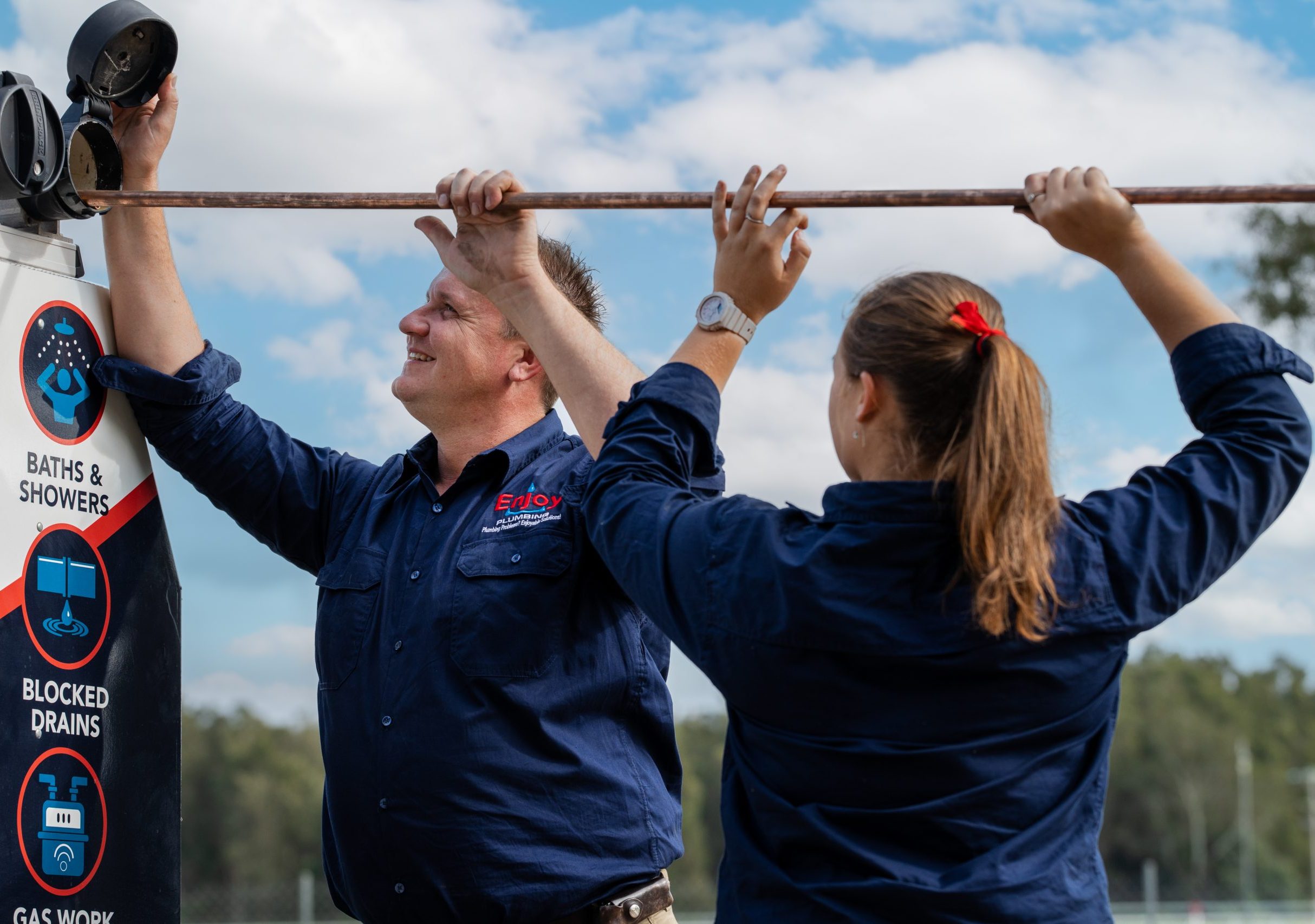 Two Enjoy plumbers carrying pipe